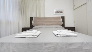 A neatly made bed with two folded towels, a wooden headboard, and a framed picture on the wall. - Obispo Oro Flat ZX6 (Córdoba)