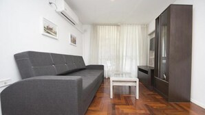 A modern living room with a grey sofa, a small white table, and a dark cabinet. - Obispo Oro Flat ZX6 (Córdoba)