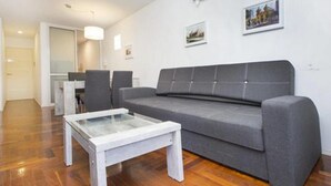 A living room with a grey sofa, a glass-top coffee table, and a wooden floor. - Obispo Oro Flat ZX6 (Córdoba)
