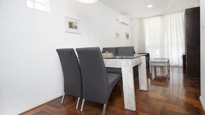 A dining area with a glass table and chairs, white walls, and wooden flooring. - Obispo Oro Flat ZX6 (Córdoba)