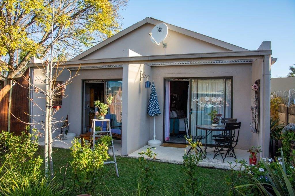 Ein modernes Haus mit Satellitenschüssel, einer Terrasse mit Tisch und Stühlen sowie einem Garten mit verschiedenen Pflanzen.