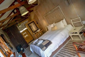 A bedroom with a bed, a wooden chair, a small table, and a window with blinds. - Mirabel Guesthouse (Ngwathe)