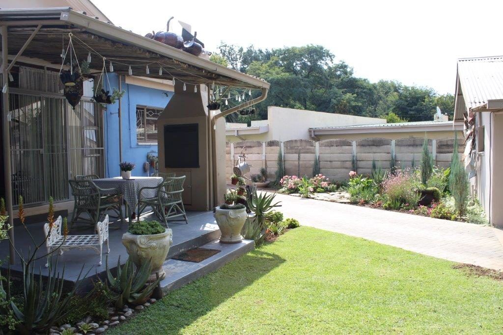 A patio with outdoor furniture, a covered seating area, and a garden with various plants and flowers.