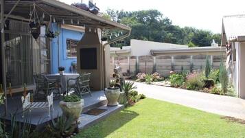 A patio with outdoor furniture, a covered seating area, and a garden with various plants and flowers.