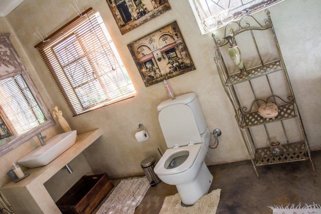 A bathroom with a toilet, sink, and decorative shelves.