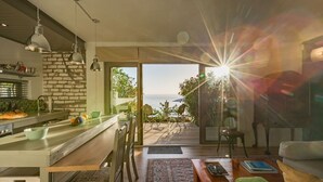 A modern kitchen with a brick wall, a dining area with a view, and a cozy living space with a sofa and a coffee table. - Watercolours Studios (Cape Town)