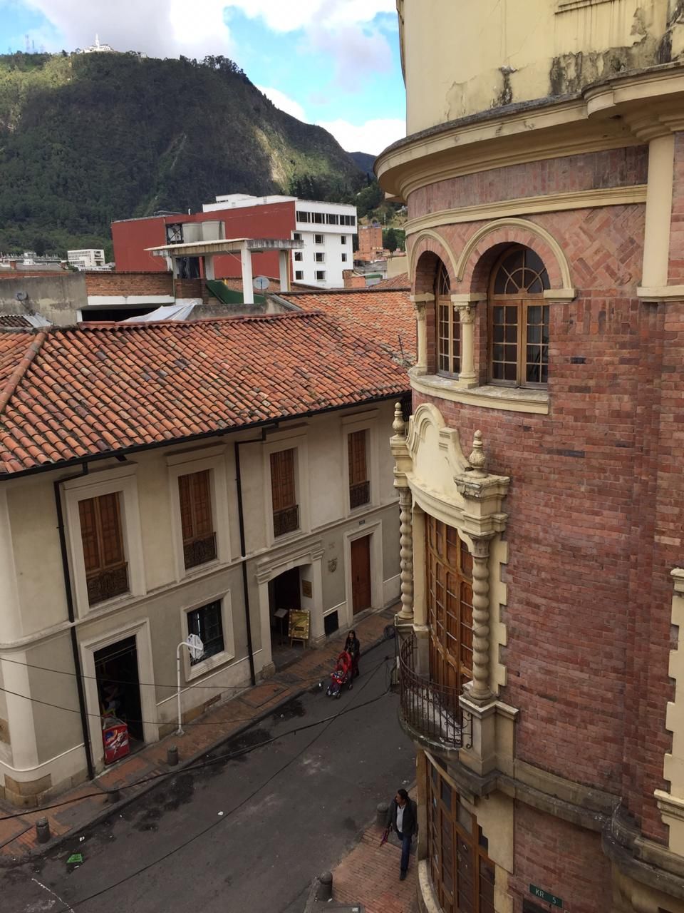 A street view with buildings, a street, and a mountain in the background.