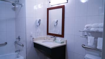A modern bathroom with a bathtub, a sink with a mirror, and a toilet.
