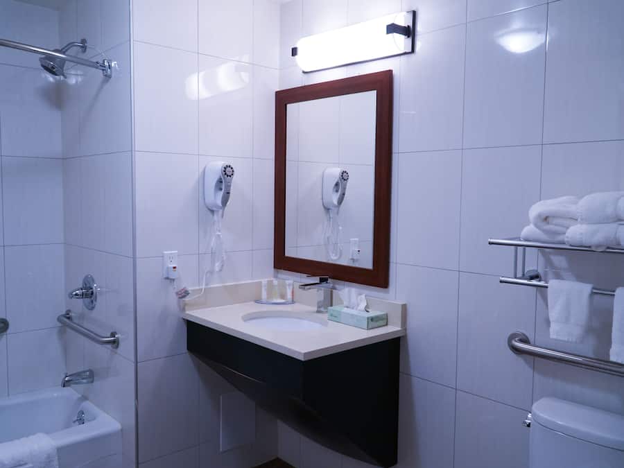 A modern bathroom with a bathtub, a sink with a mirror, and a toilet.