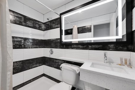 Ensemble douche/baignoire, articles de toilette gratuits, sèche-cheveux. Hotel Mint JFK Airport