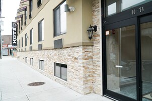 Fachada de hotel con revestimiento de piedra, ventanas amplias y puerta de entrada negra.
