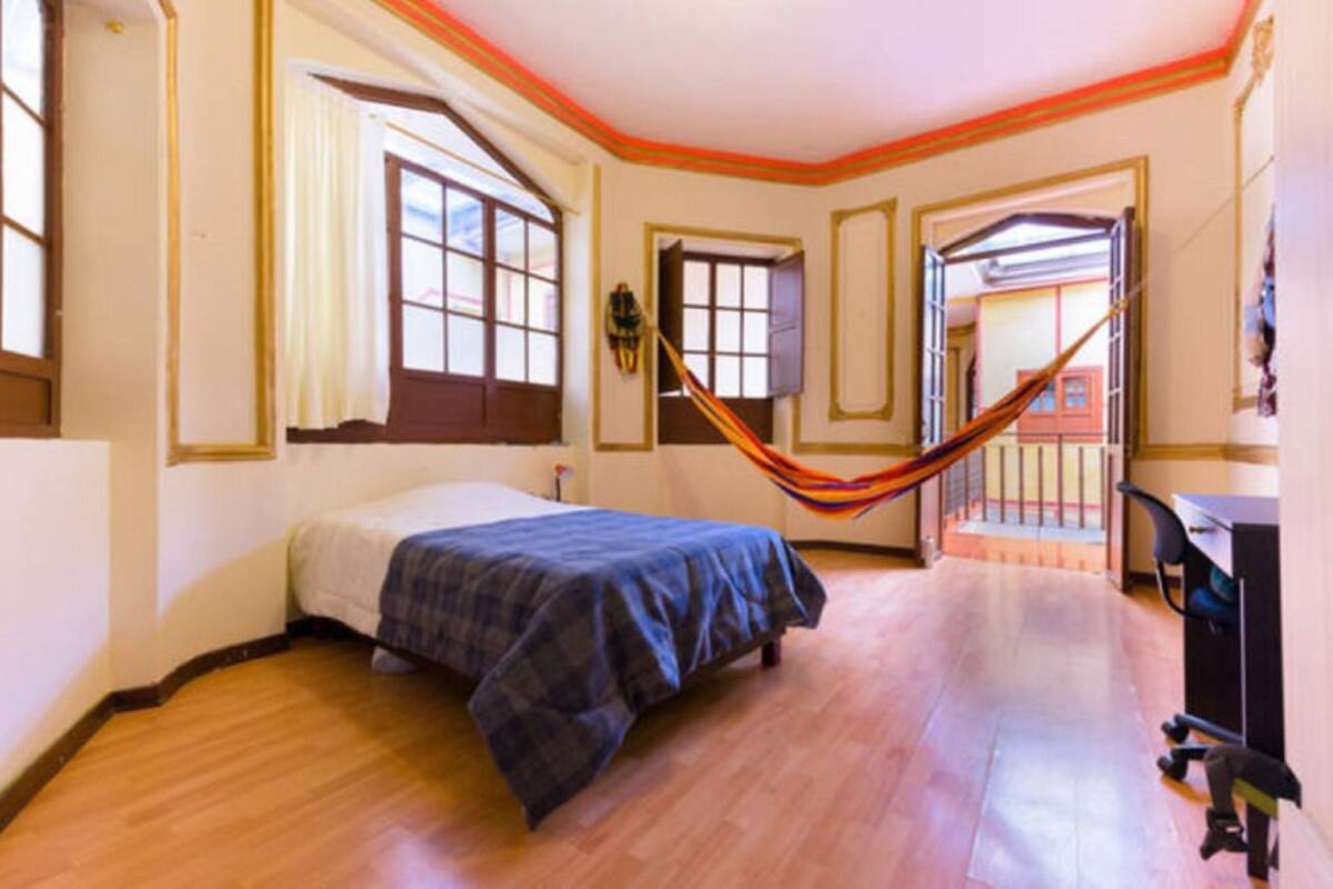 A bedroom with a bed, a desk, and a hammock.