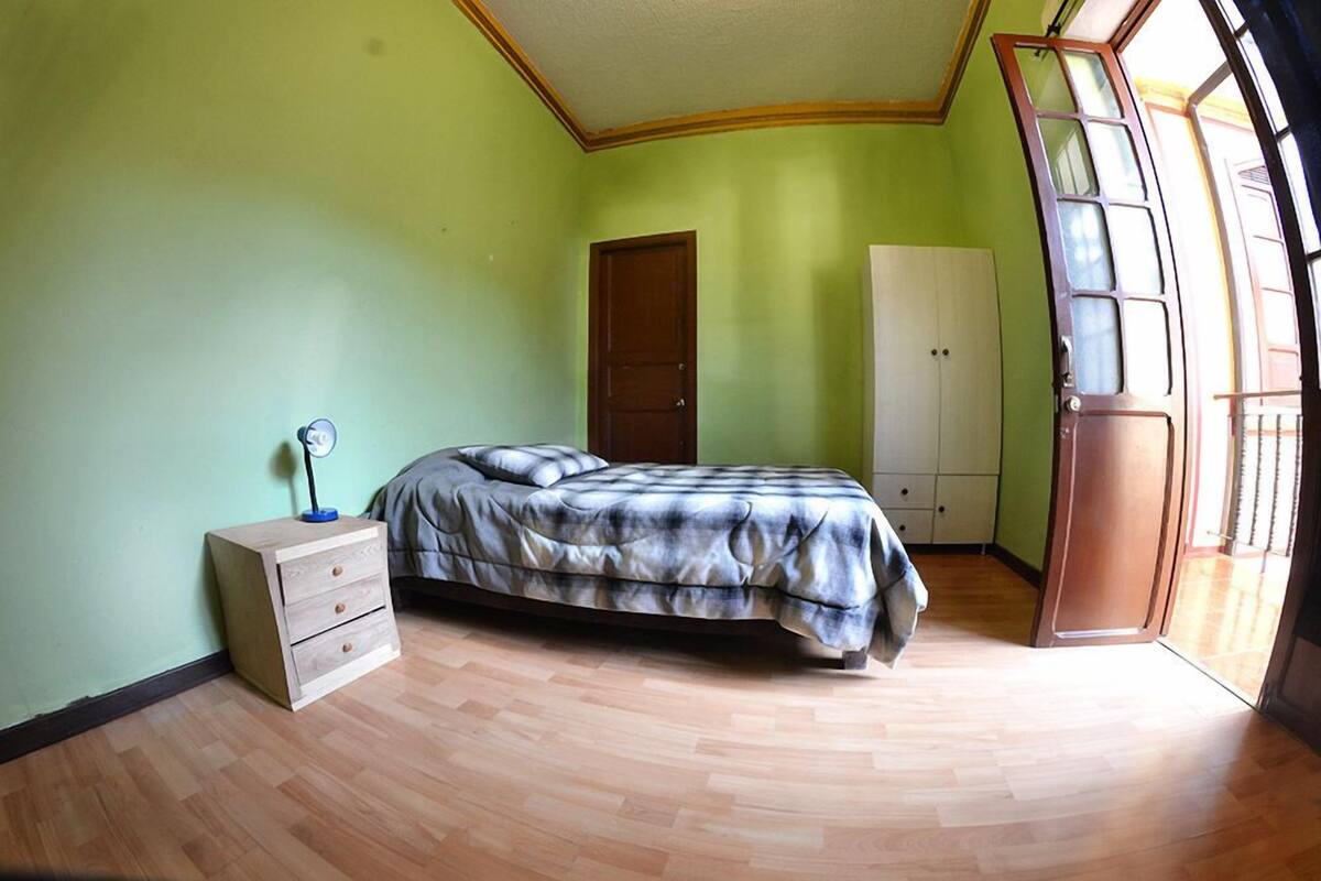 A bedroom with a bed, a nightstand, a wardrobe, and a door leading to a balcony.