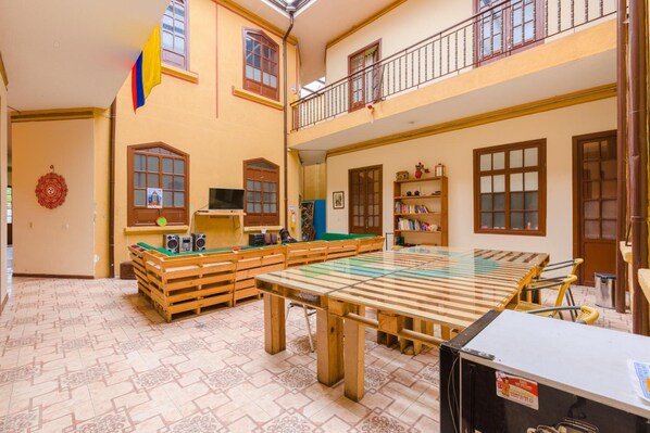 Una habitación amplia con mesa de billar, bancos de madera y un balcón.