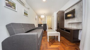 A modern living room with a grey sofa, a white coffee table, and a TV mounted on a wall. - Obispo Oro Flat ZX1 (Córdoba)