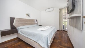 A bedroom with a bed, a mounted TV, and a window with curtains. - Obispo Oro Flat ZX1 (Córdoba)