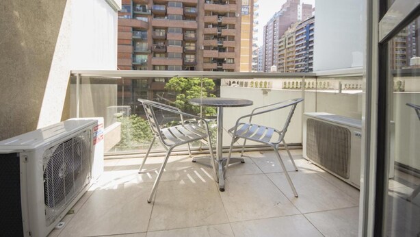 A balcony with two metal chairs and a small table, overlooking a cityscape with high-rise buildings. - Obispo Oro Flat ZX1 (Córdoba)