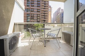 A balcony with two metal chairs and a small table, overlooking a cityscape with high-rise buildings. - Obispo Oro Flat ZX1 (Córdoba)