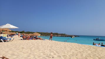 Playa en los alrededores, playa de arena blanca, camastros y sombrillas 