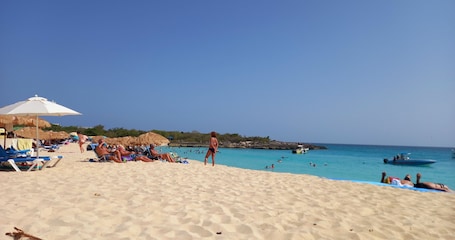 Una playa cerca, arena blanca, sillas reclinables de playa, sombrillas