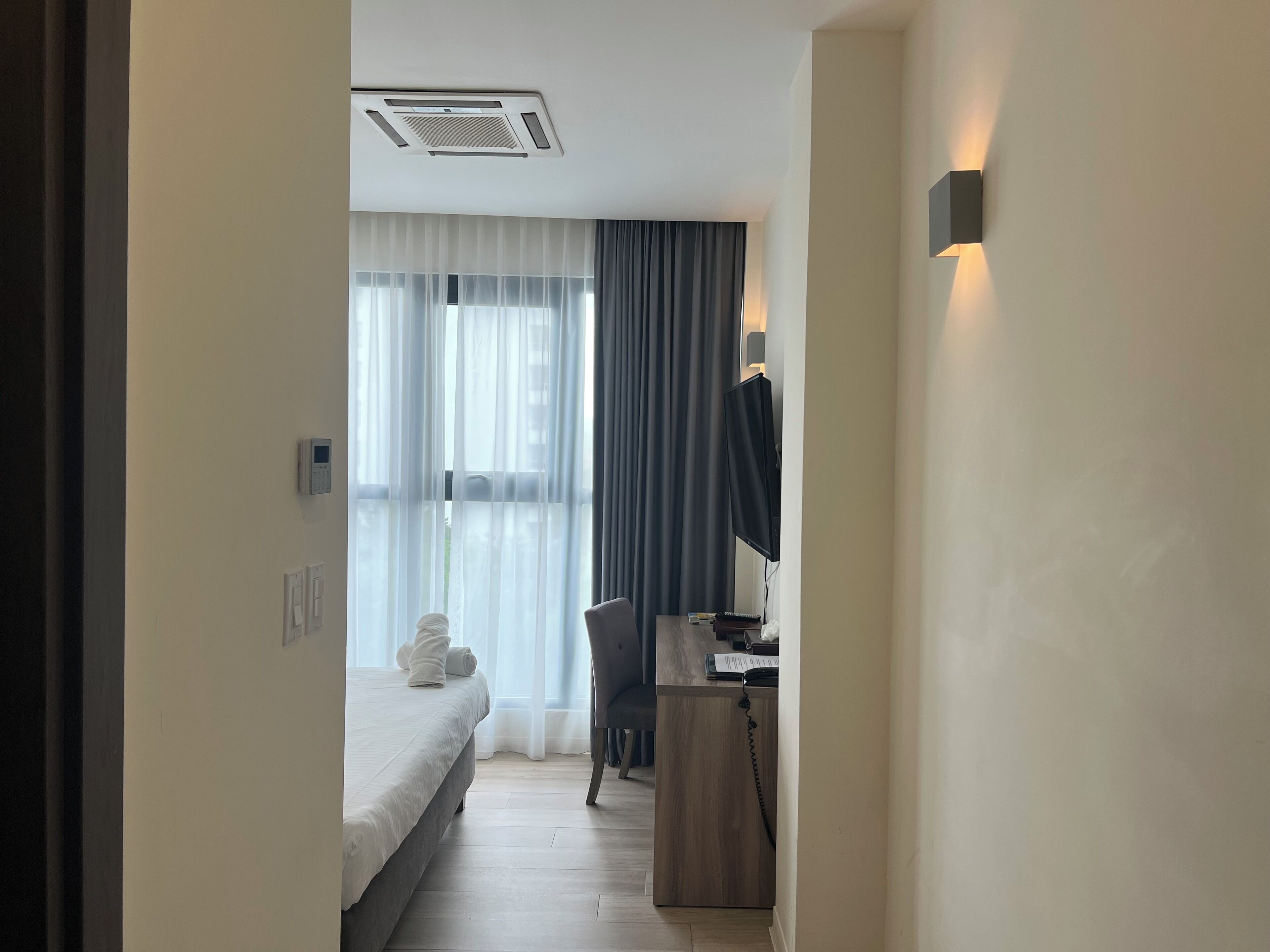Una habitación de hotel con cama, escritorio, silla y televisor.