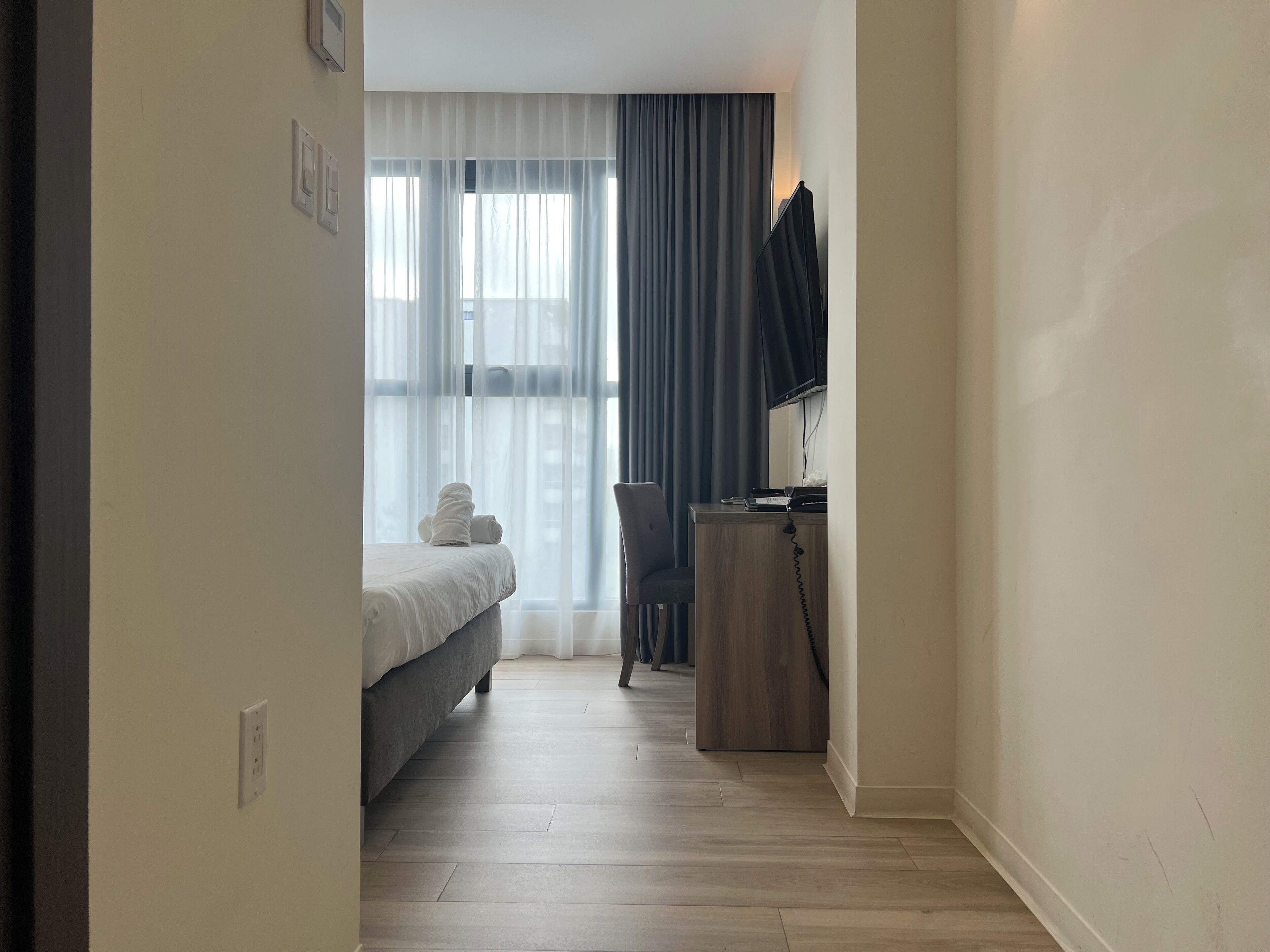 Une chambre d’hôtel avec un lit, un bureau avec un téléphone et une chaise.