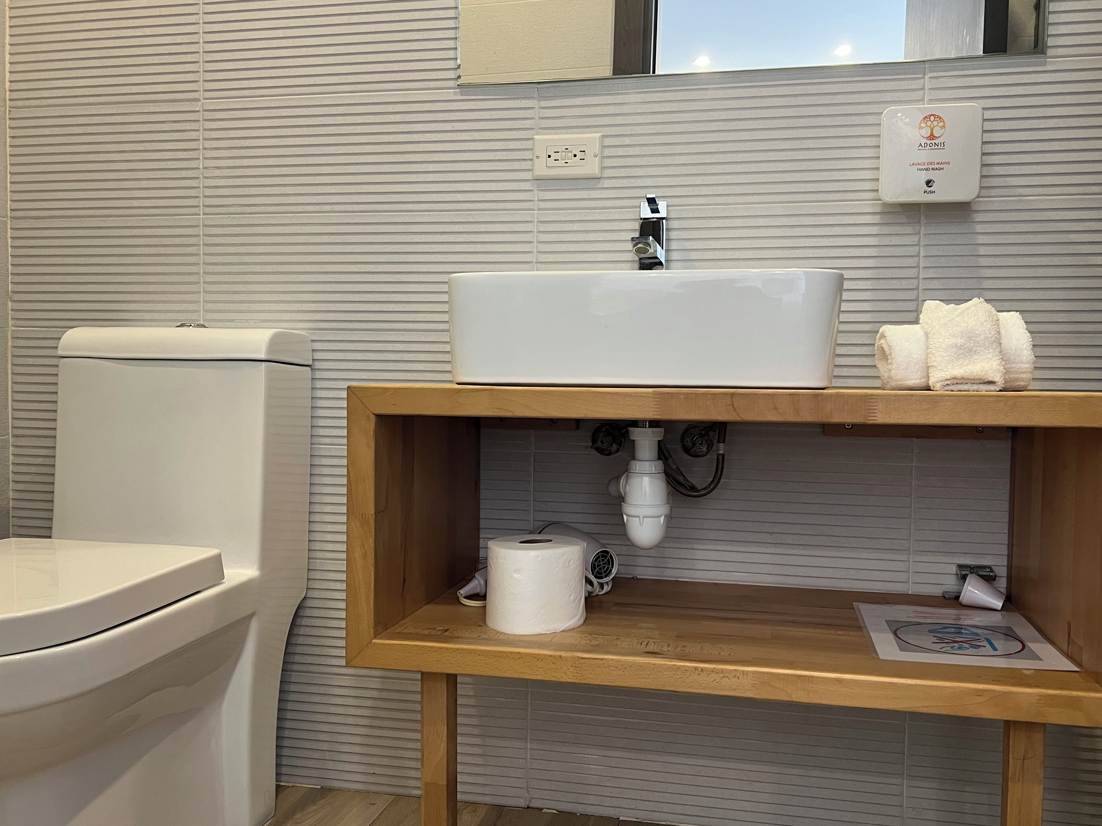 A bathroom with a toilet, sink, and wooden vanity.