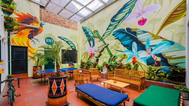 An indoor courtyard with a mural, seating, and a ping pong table. - La Quinta - Hostel (Bogotá)