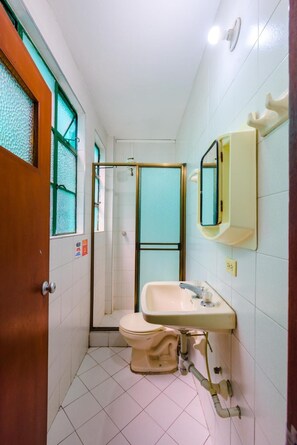 A compact bathroom with a toilet, sink, and shower area. - La Quinta - Hostel (Bogotá)