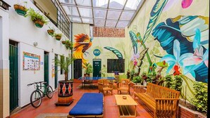 A courtyard with a mural, seating, and a bicycle. - La Quinta - Hostel (Bogotá)