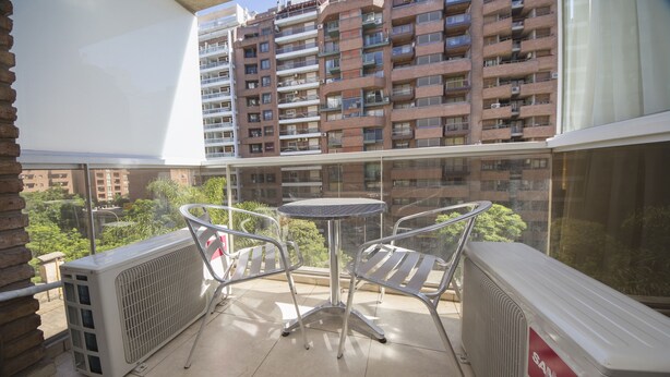 Ein Balkon mit Tisch und Stühlen, einer Sanyo-Klimaanlage und Blick auf hohe Gebäude.