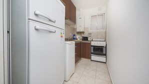 Eine kleine Küche mit einem weißen Kühlschrank, einer Kaffeemaschine, einem Toaster und einem Herd.