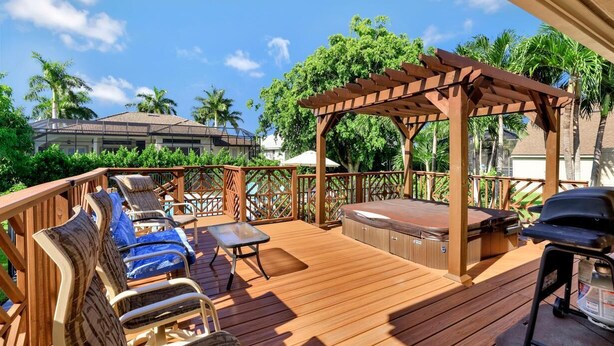 A wooden deck with outdoor seating, a hot tub, and a pergola. - 601 Lewis Court (Marco Island)