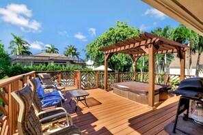 Una terraza de madera con mobiliario exterior, un jacuzzi y una pérgola.