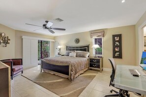 A bedroom with a bed, bedside tables, a desk, and a chair. - 601 Lewis Court (Marco Island)
