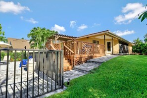 A residential property with a covered patio, a staircase leading to a second floor, and a well-maintained lawn. - 601 Lewis Court (Marco Island)