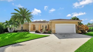 A single-story house with a beige exterior, a red-tiled roof, and a white garage door. - 601 Lewis Court (Marco Island)