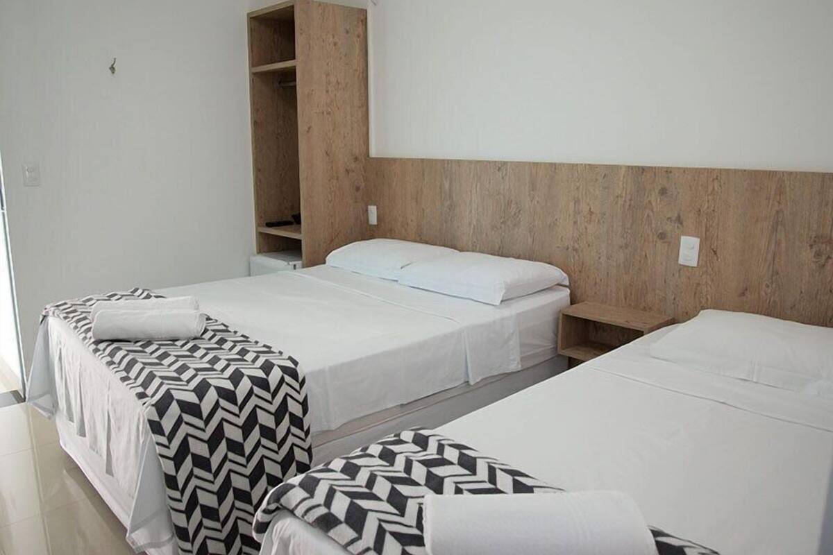 A hotel room with two single beds, a wooden headboard, and a built-in wardrobe.
