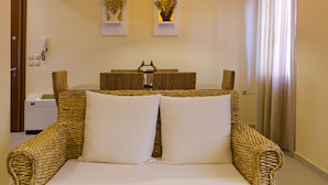 A room with a woven sofa bed, a small table with a lamp, and wall-mounted artwork. - Cashel House (Corfu)