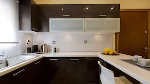 A modern kitchen with dark cabinetry, a white countertop, and a breakfast bar. - Cashel House (Corfu)