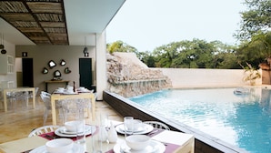 Comedor con una mesa preparada para cuatro personas, con vista a una piscina.