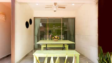 A dining area with a table and benches, a ceiling fan, and a window with curtains.