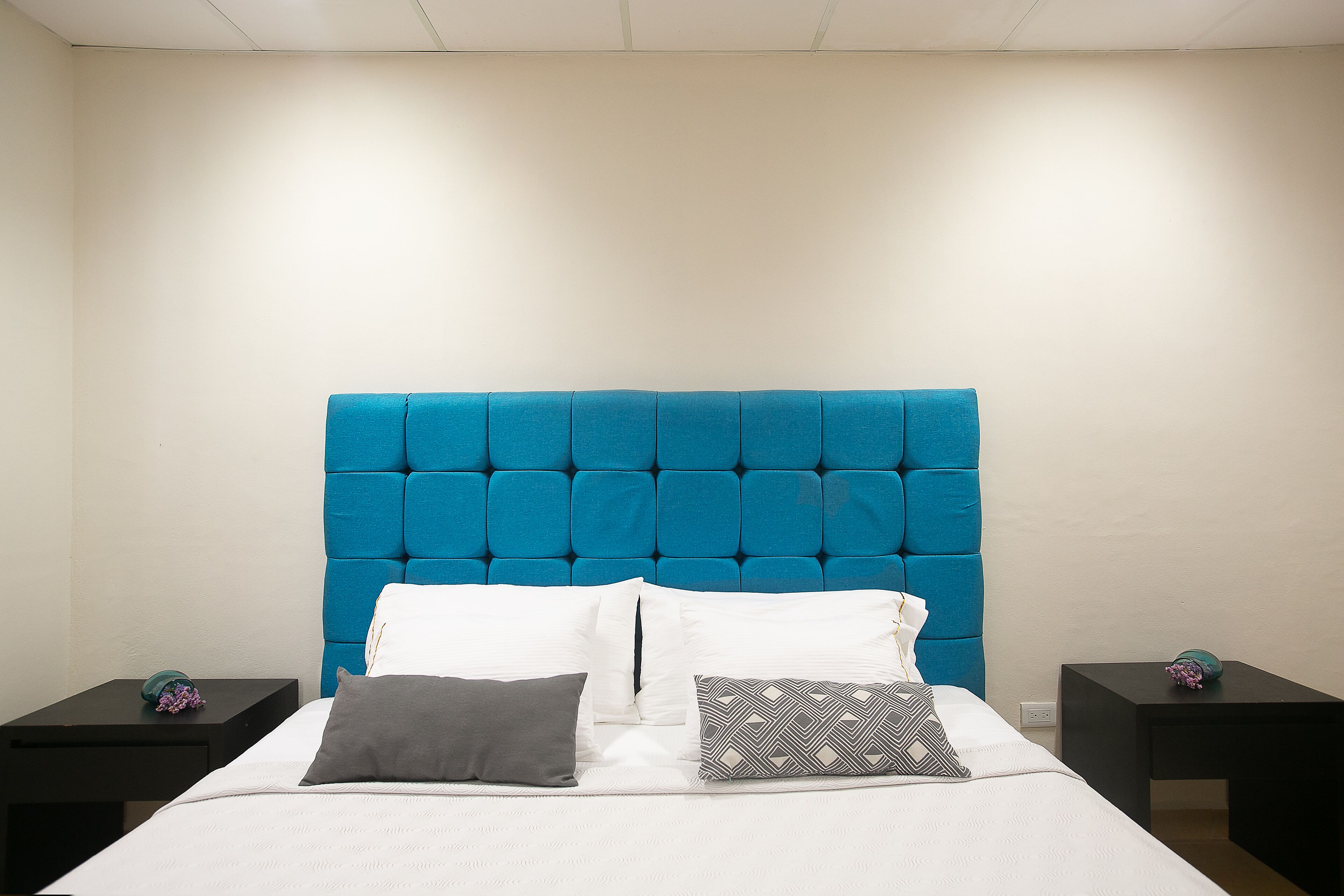 Ein Bett mit blauem Kopfteil, weißer Bettwäsche und zwei Nachttischen mit Dekoration.