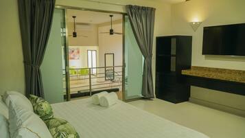 Habitación de hotel con cama, cortinas, televisión y balcón.