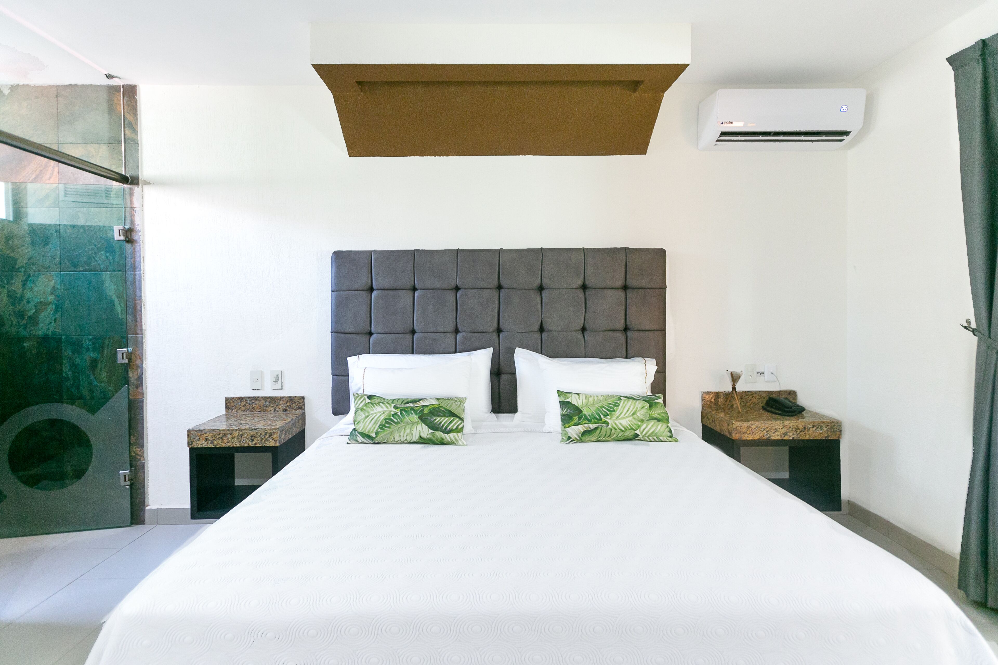 Een moderne hotelkamer met een groot bed, twee nachtkastjes, een hoofdeinde en een airconditioning.