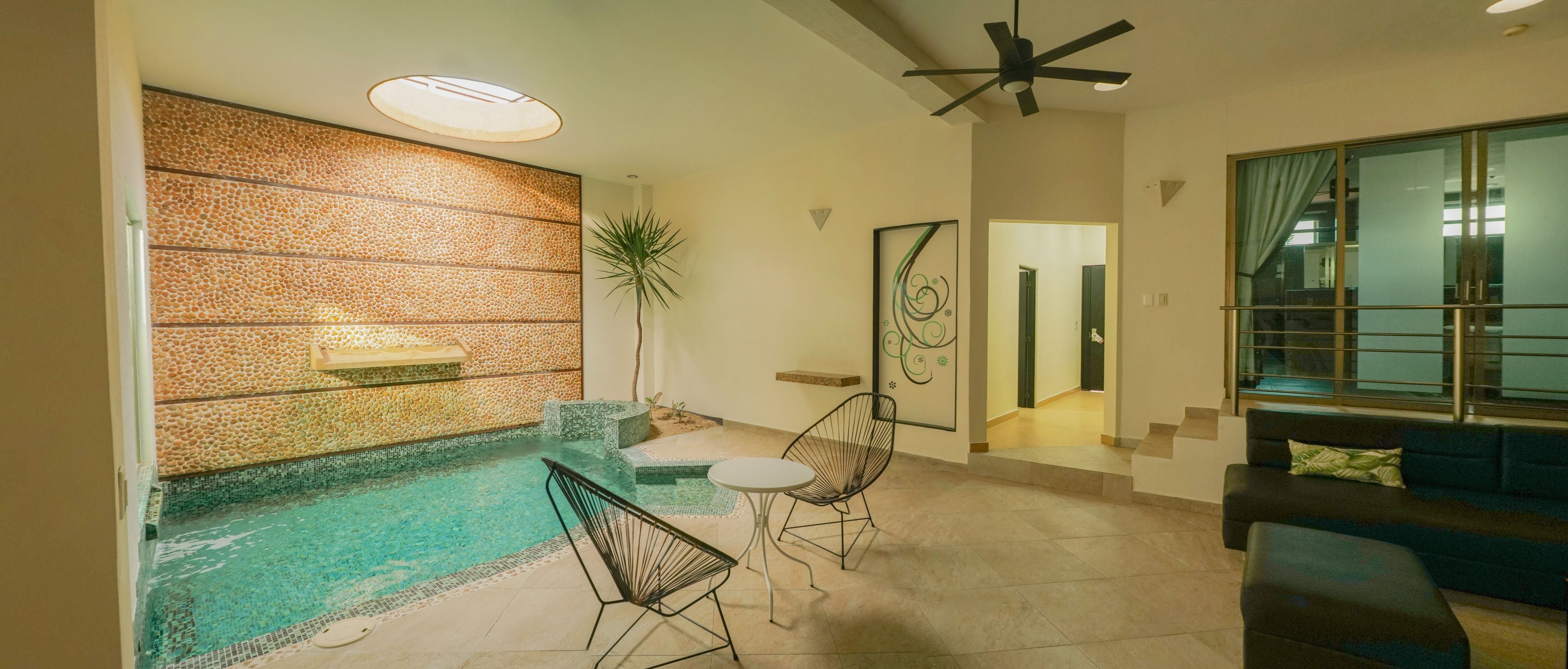 Un salon moderne avec une piscine, un ventilateur de plafond et un escalier menant à un autre niveau.