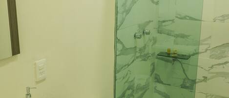 Een badkamer met een douchecabine van glas, een wit wastafelmeubel en een toilet.