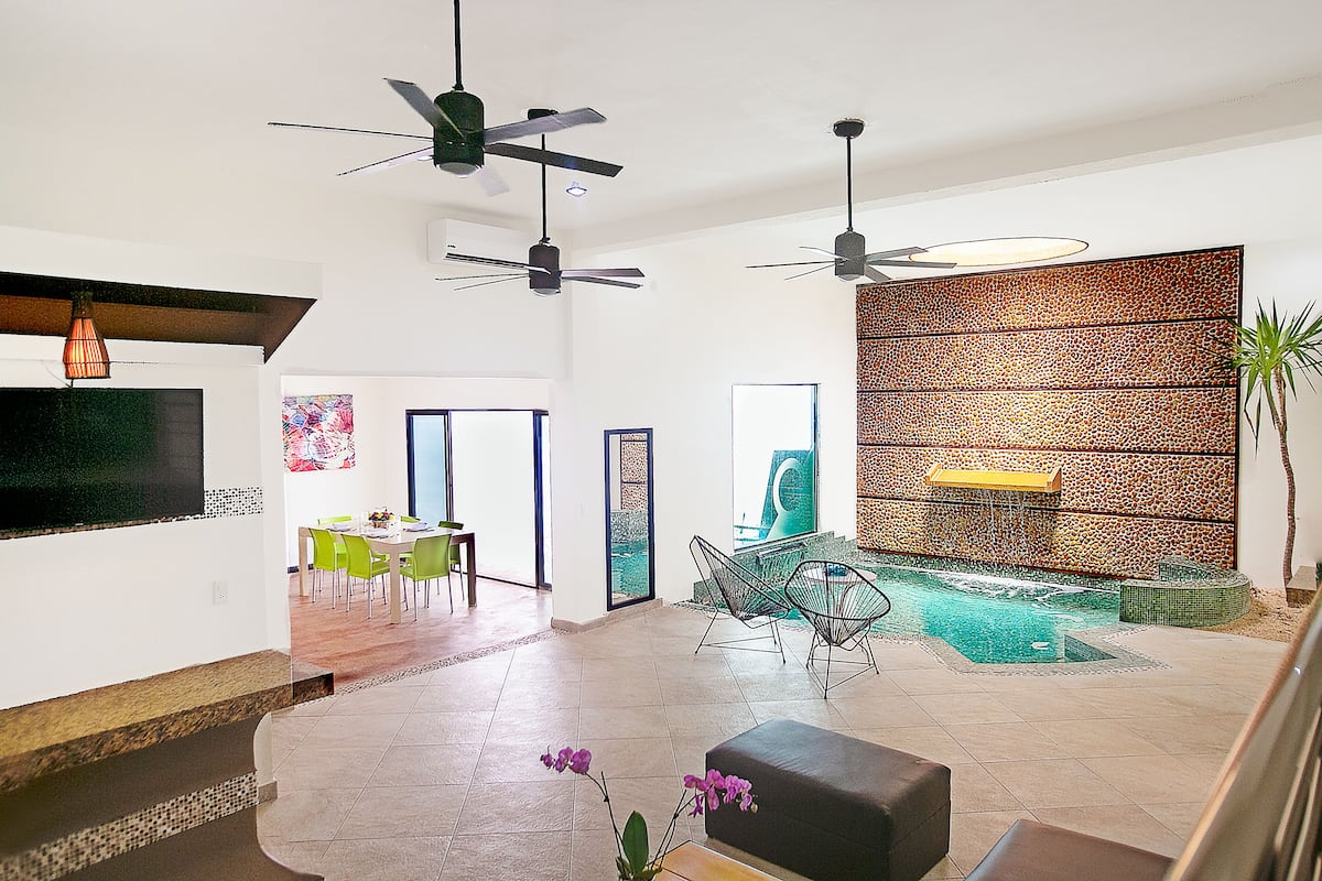 A spacious living area with a pool, ceiling fans, and modern furniture.