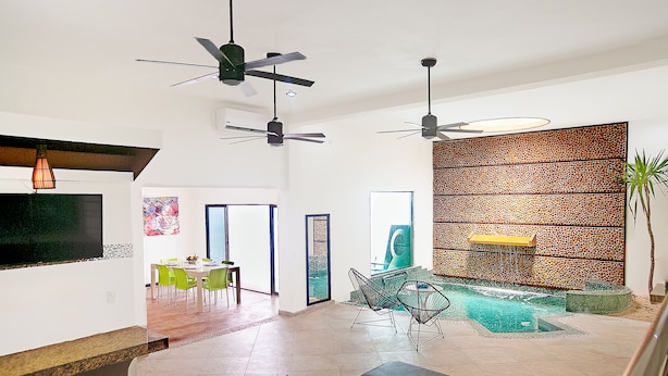 Amplia sala de estar con piscina, ventiladores de techo y muebles modernos.