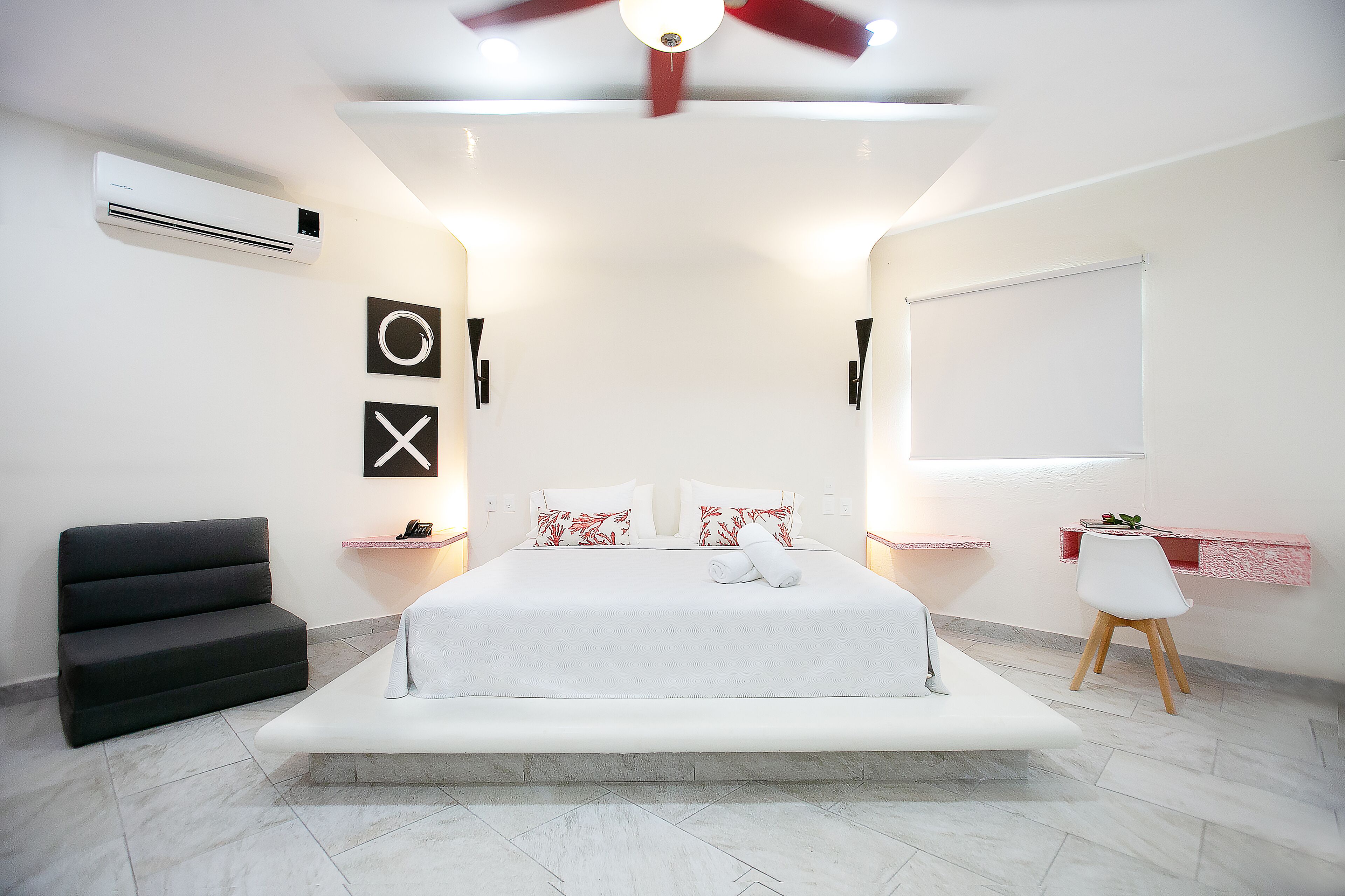 A modern bedroom with a large bed, bedside tables, a ceiling fan, and a window.